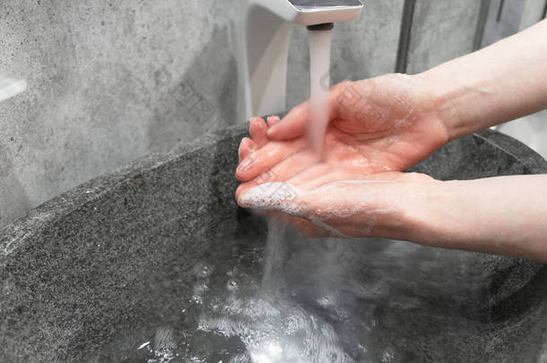 大肠病毒大流行病的预防。用肥皂和温水洗手。擦拭指甲和手指妇女在自来水下洗手.