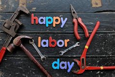 劳动节快乐文字在木制背景上的红色建筑维修工具。劳动节概念标志.快乐的工作日-写作螺丝.