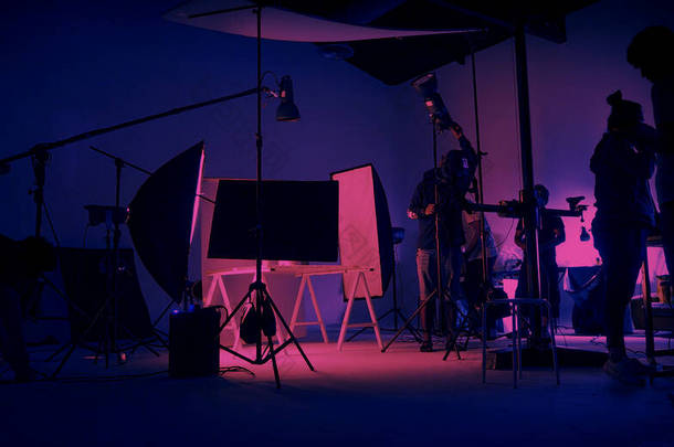 纽蓝粉的色彩拍摄。在大工作室里的视频制作现场后面。摄制组工作和<strong>摄像</strong>设备在轮廓中.电影制作行业。安装照明装置.