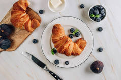 早餐，一杯咖啡，新鲜羊角面包和成熟的浆果，白色大理石背景。顶部视图