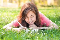 幸福年轻的亚洲女人写在笔记本和微笑