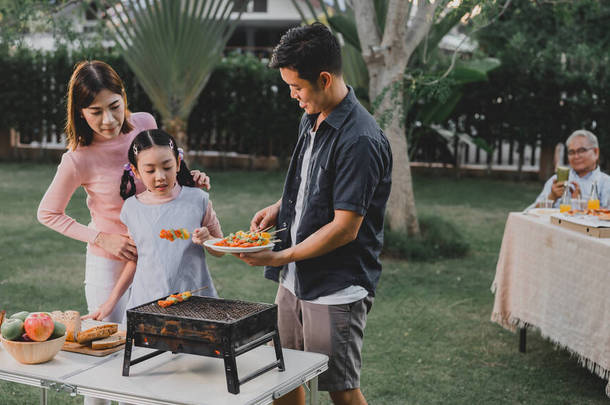 亚洲家庭在家里举办<strong>烤肉派对</strong>。在后院里烹调<strong>烤肉</strong>当晚餐.暑假的生活方式.