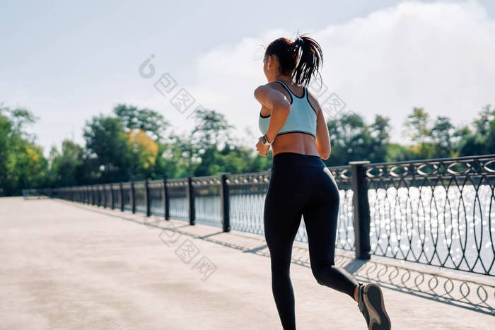 一个健康的女人从河边跑到户外的背景。穿着运动服在户外慢跑的漂亮女人。动态运动.                            