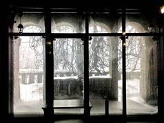 玻璃上有霜冻，石拱形阳台上有新年装饰，从彩色玻璃窗上眺望