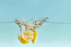 黄色成熟的柠檬深落水中，蓝色背景上飞溅