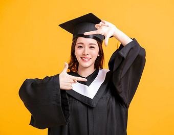 毕业时快乐的年轻女子穿着长袍，摆出一副笑脸