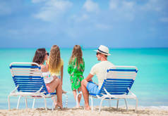 四在海滩上的幸福美丽的家庭。父母放松日光浴和孩子在海边玩得开心