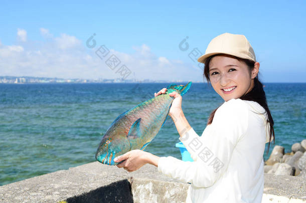 抱着大鱼的微笑的年轻女子