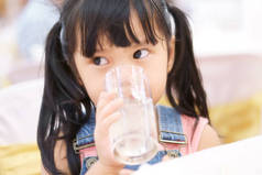 亚洲儿童可爱或小女孩口渴，喝冰镇在玻璃杯里的冷水有利于健康