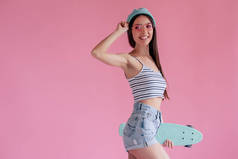 年轻的亚裔少女粉红色的背景粉红色的眼镜。滑板女孩在短裤与滑板隔离.