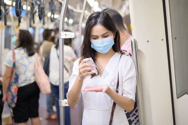 一名戴防护面具的年轻女子在地铁里用酒精洗手、携带Covid-19流感、安全旅行、<strong>社交礼仪</strong>、新的正常旅行理念