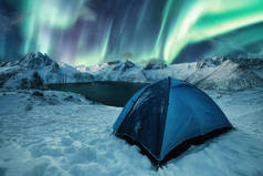 挪威森贾岛雪山上的蓝色帐篷，与奥罗拉 · 波瑞斯在山脉上跳舞