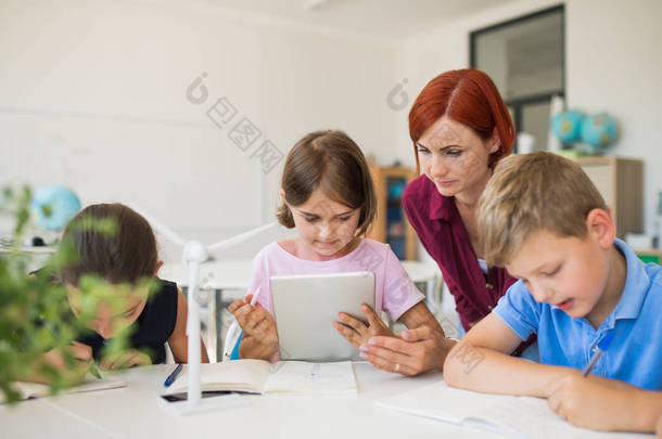 一群小学校的<strong>孩子</strong>，<strong>老师</strong>在课堂上围成一圈，使用平板电脑.