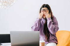 年轻女人在使用前置笔记本电脑的眼镜后，会揉揉眼睛。眼睛疼痛或疲劳的概念