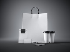 一套白色工艺购物袋、两个咖啡杯、名片和通用设计智能手机。黑暗的
