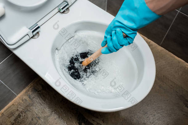 在用灰色<strong>瓷砖</strong>冲洗现代卫生间时，水管工在马桶中使用柱塞的剪影
