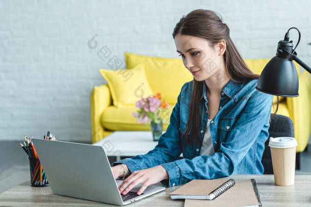 在家学习时使用笔记本电脑的微笑的女孩