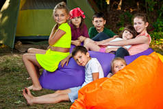 孩子们在远足时休息.男孩和女孩在充气沙发上玩耍。在大自然中度过暑假。后面是帐篷。帐篷里的游戏.