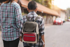 带着背包带着亲生儿子或学生上学的母亲或父母，回到学校的概念，有选择的重点.