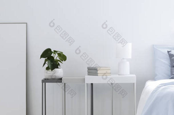 一张蓝色床的真实相片站立在桌旁边与植物、书和灯和样机框架在轻的卧室内部