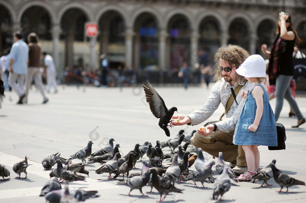 可爱小女孩和她父亲喂鸽子