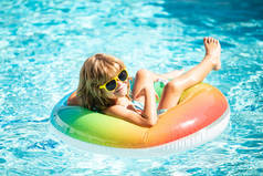 夏天的假期。夏天的孩子周末。在水上公园的充气橡胶圈上游泳的有趣男孩.