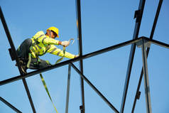 建筑工地的建筑工人系好安全带在高处工作.
