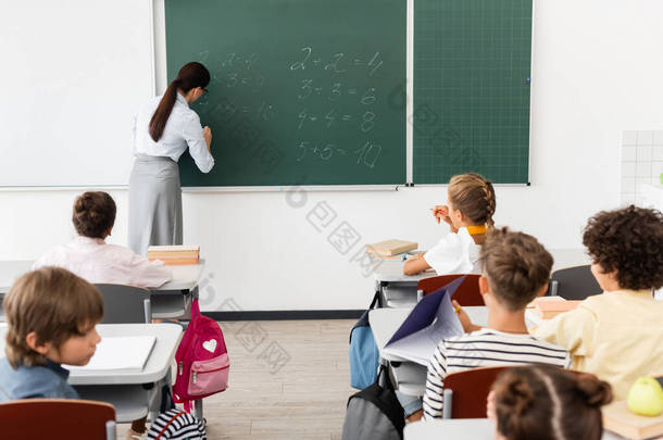 数学课期间，多文化学生附近黑板上教师写作方程的<strong>回顾</strong>