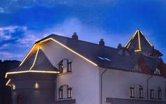 奢华时尚的豪宅，屋顶上点缀着带条纹的彩带，在漆黑的天空中，是圣诞前夕装饰的现代住宅的景观.