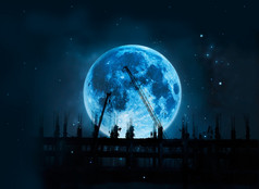 施工现场吊车和工人在夜晚的蓝色满月
