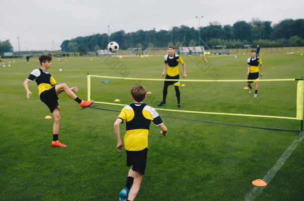 少年足球俱乐部的男孩子们在打足球网球训练比赛.青少年足球运动员在训练课上打网球.青少年在草地上练习足球. 