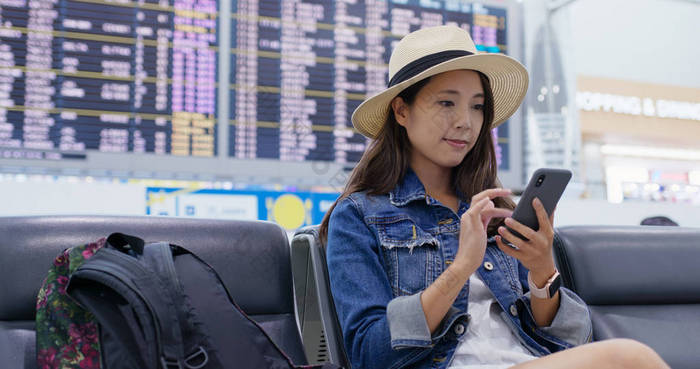 女人用智能手机检查空中的飞行时刻表