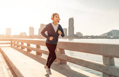 年轻的女运动员跑步和城市背景。健康与户外运动概念.