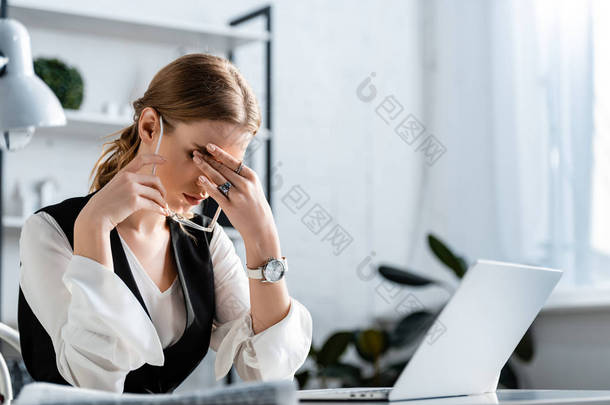 女商人穿着正式的衣服坐在电脑桌前, 触摸额头, 并在工作场所<strong>头痛</strong>