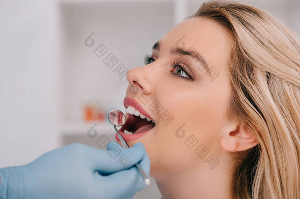 <strong>牙医</strong>检查年轻妇女的牙齿与嘴镜子