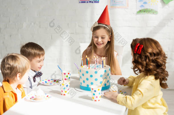 可爱<strong>的快乐的孩子</strong>们坐在派对桌上吃蛋糕, 同时一起庆祝生日