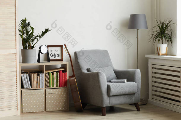 现代简约室内环境中舒适的阅读角落的背景图像，聚焦于靠墙的灰色扶手椅上，复制空间