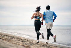男子和女子赛跑选手在海滩上训练