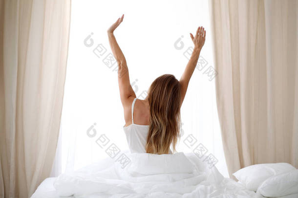 女人醒来后躺在床上，回头看，<strong>进入</strong>快乐和放松的一天，睡了个好觉。美梦，早上好，新的一天，周末，假期的概念