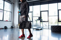 美国黑人男子在运动装袋和瓶装水在健身房拍摄