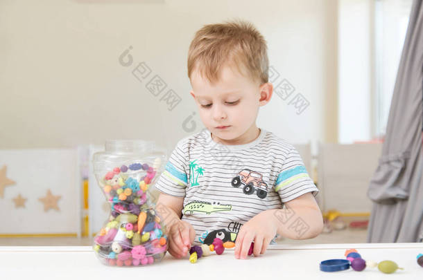 一个小男孩正在玩珠子和其他小玩具。消遣在孩子庭院或戏剧中心