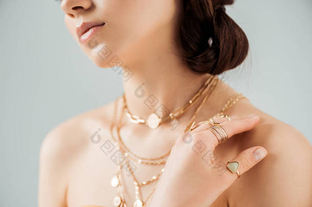 裁剪视图的年轻女子与闪亮的嘴唇在金项链和戒指隔离在灰色