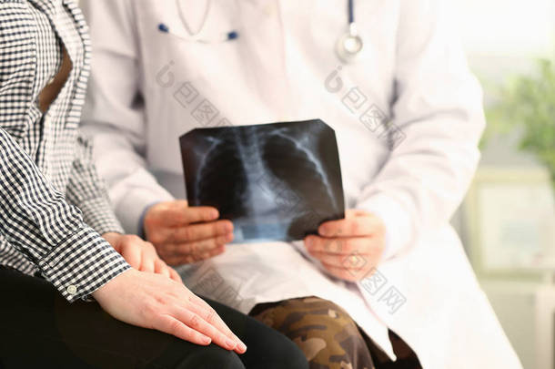 医生拿着病人的X光片，报告坏消息