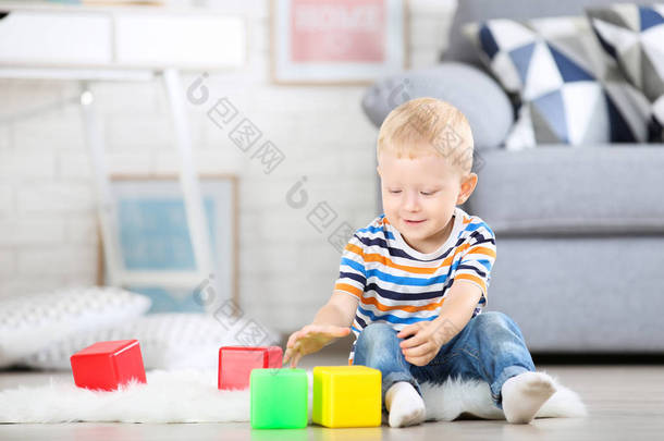 小男孩坐在白色的地毯在家里玩科洛