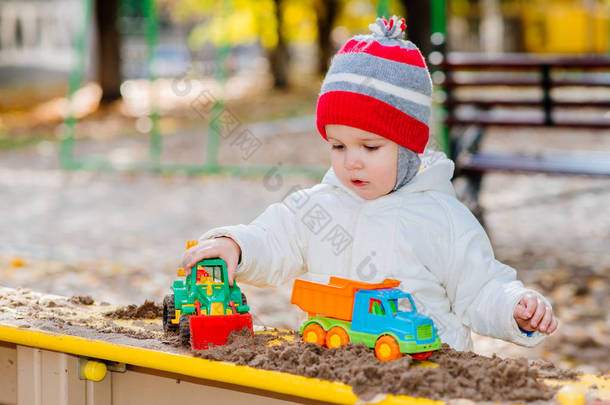 孩子在街上的沙箱里玩汽车