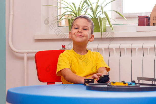 穿着黄色T恤的小男孩在家里玩汽车和玩具，在室内