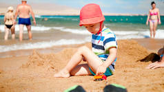 3岁幼儿在海边与玩具车的合影。儿童在暑假假期放松和享受乐趣.