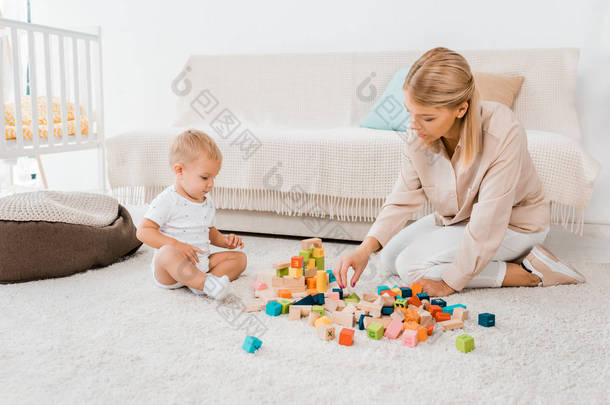 可爱的<strong>幼儿</strong>玩五颜六色的立方体和母亲在托儿所室