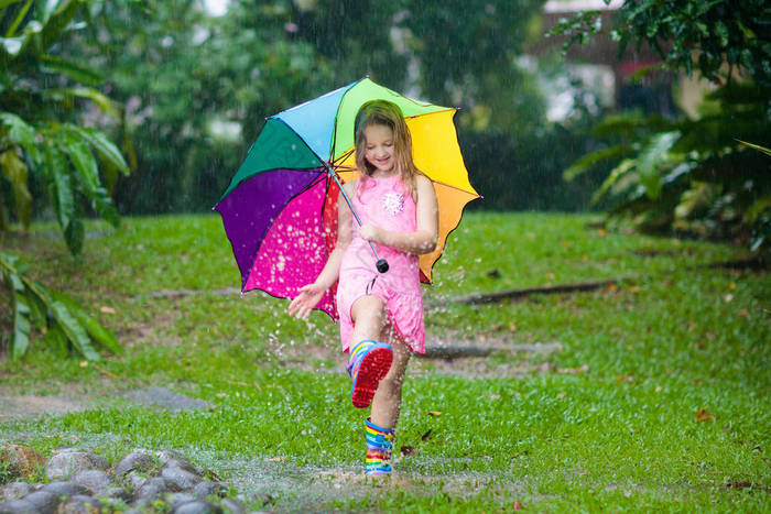 孩子在雨中玩耍。孩子们穿着雨伞和雨靴在外面大雨倾盆地玩耍.小女孩在泥泞的水坑里跳跃.孩子们被秋天的雨天逗乐了.在热带风暴中奔跑的儿童.