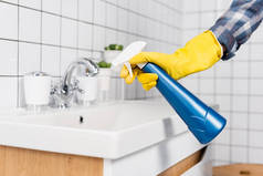 女用橡胶手套在浴室洗涤槽上使用洗涤剂的剪影 